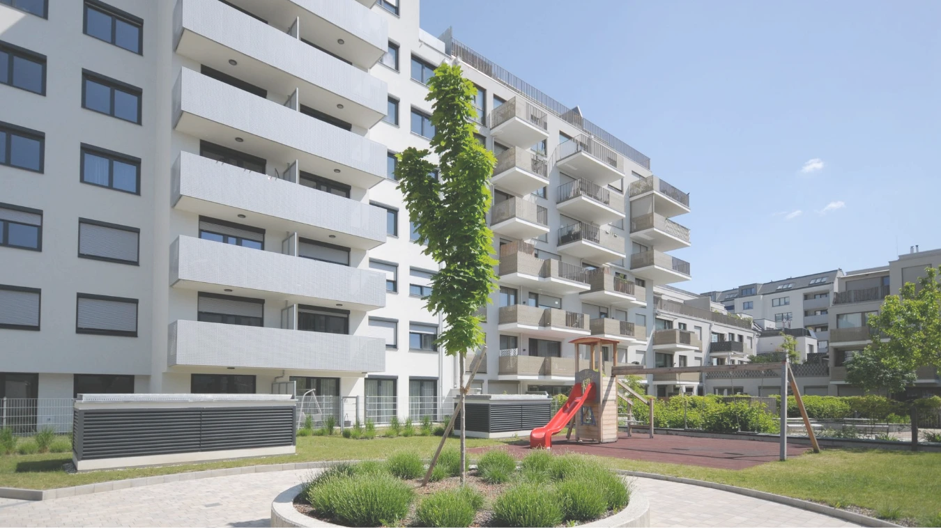 Moderner Wohnbau mit Spielplatz und Begrünung im Innenhof.
